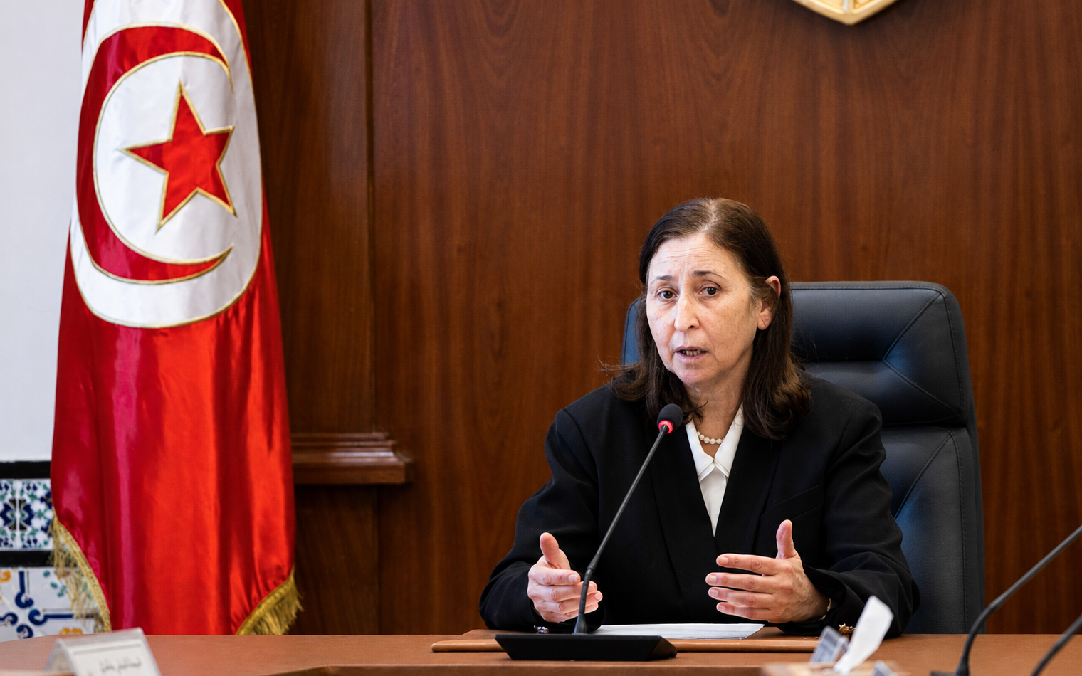 Sarra Zaafrani Zenzri s’exprime devant le drapeau tunisien.